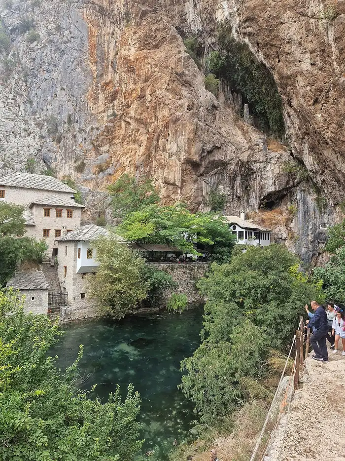 The Blagaj dervish house complex tucked against a huge limestone cliff and cave, the clear green Buna spring pool below