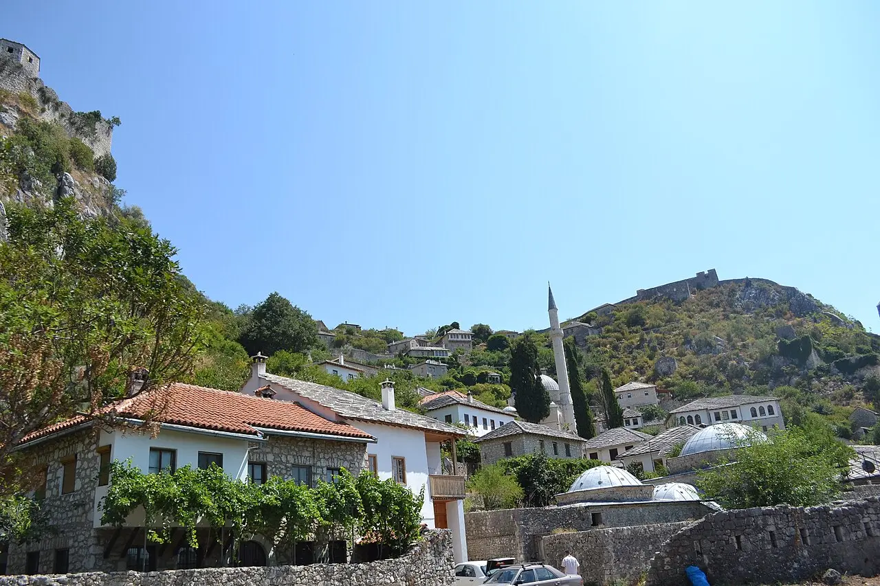 The village of Počitelj climbing a hillside above the Neretva, stone houses, a mosque minaret and domes with the fortress on the ridge above