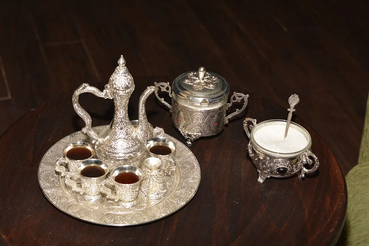 A small cup of coffee served with a copper pot and a piece of Turkish delight