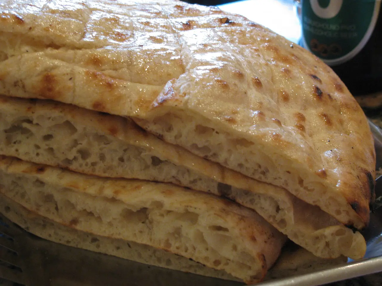 A stack of freshly baked somun flatbreads with scored crosshatch tops