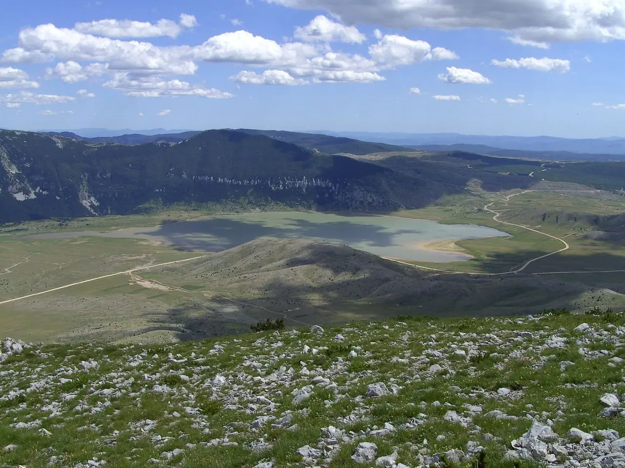 Shallow Blidinje Lake filling a high karst basin with mountain ridges beyond