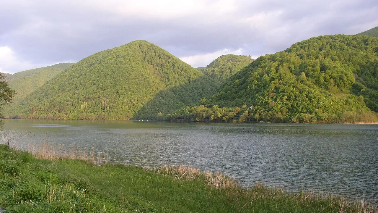Wide green expanse of Veliko Plivsko Lake near Jajce under soft summer cloud