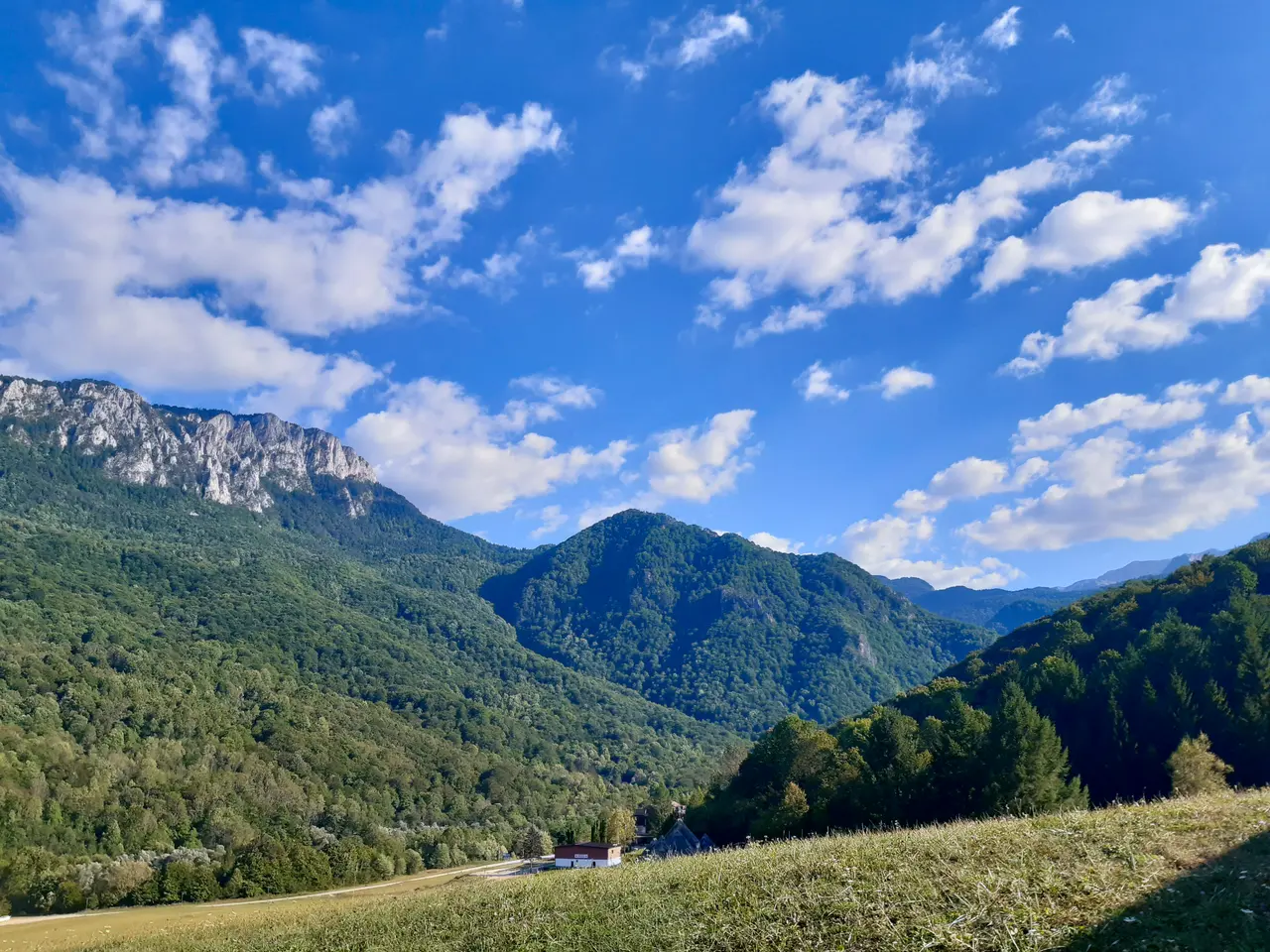 Green forested mountains and a limestone ridge under a bright blue sky in the Bosnian interior