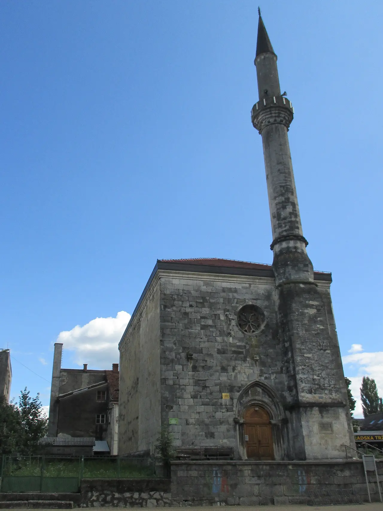 The Fethija mosque in Bihac: a Gothic stone church body with a rose window and a pointed doorway, with an Ottoman minaret attached to one corner