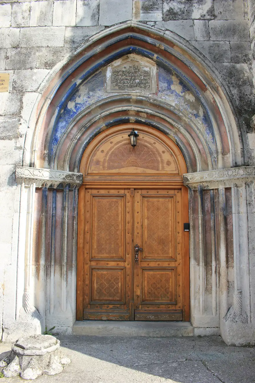 The pointed Gothic portal of the Fethija mosque in Bihac, with a carved Ottoman inscription panel set above the wooden doors