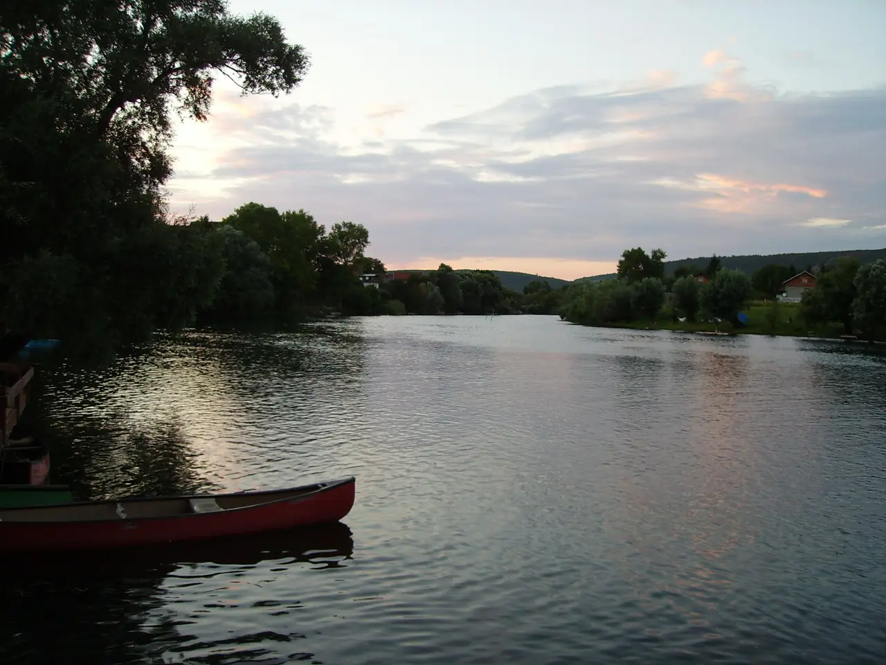The Una at dusk just south of Bihac with a red canoe pulled up on the near bank and pink cloud reflected in the water