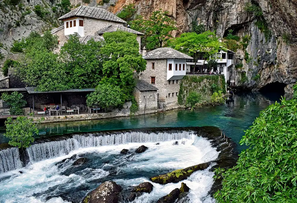 Blagaj Tekke and the turquoise Buna river seen from downstream, the cliff rising straight above the white house