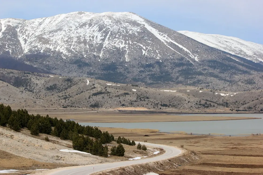 Grass and low scrub on Blidinjsko polje with the grey bulk of Mount Vran under cloud