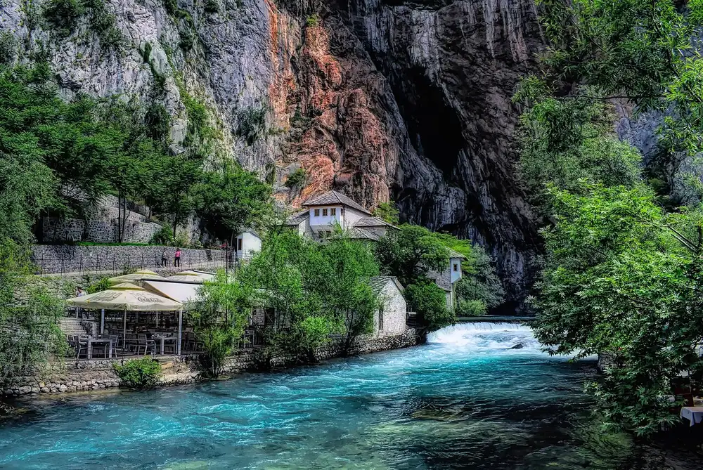 The white Blagaj dervish house at the foot of a limestone cliff beside the clear Buna river