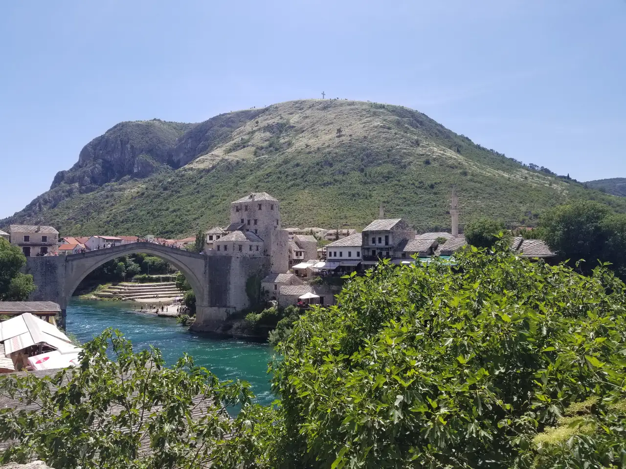 The Old Bridge (Stari Most) arching over the turquoise Neretva in Mostar old town, the diving tower and a minaret behind
