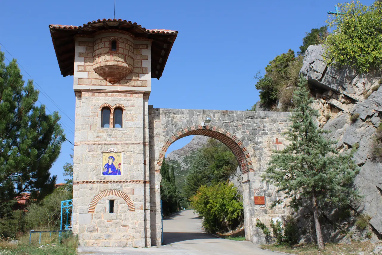 The stone bell-tower gate of Tvrdos Monastery near Trebinje under a clear sky, the road to the cellars beyond