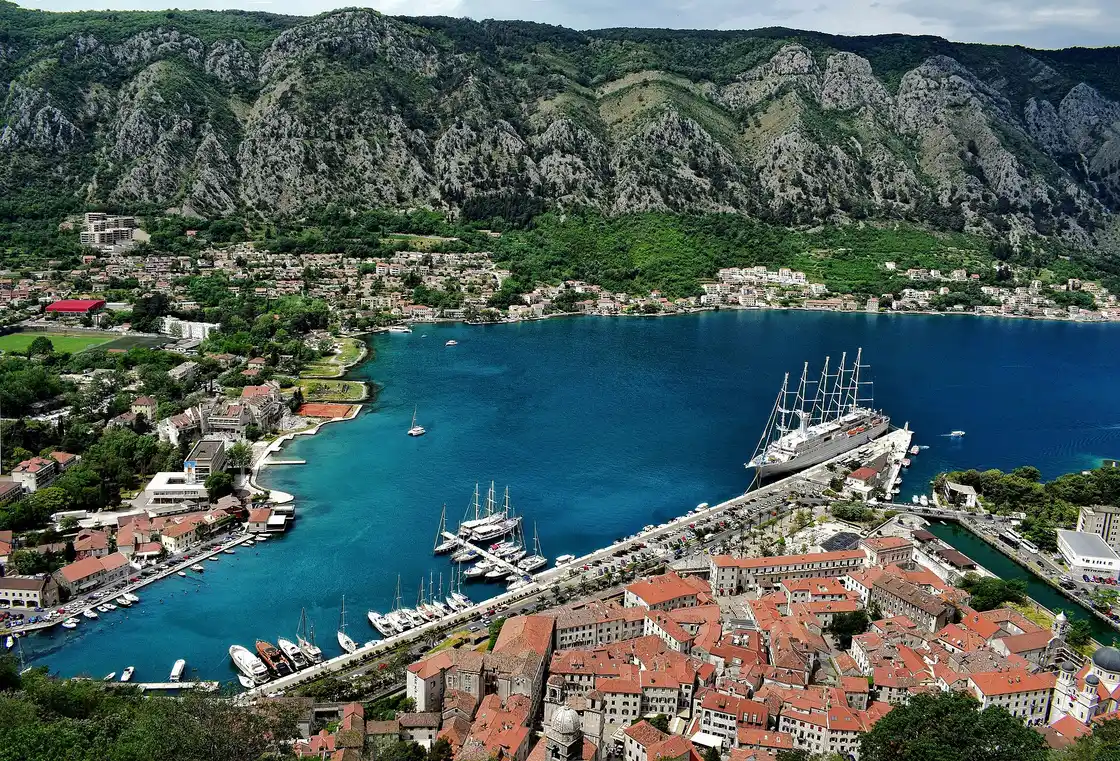 The old town of Kotor packed at the foot of a steep mountain beside the Bay of Kotor, city walls climbing the slope