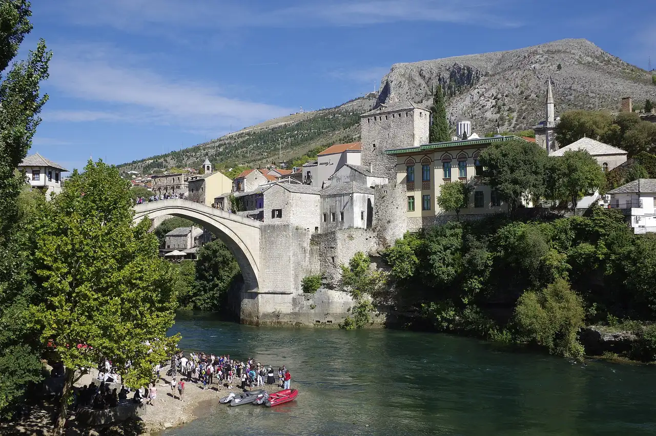 The single-arch Old Bridge of Mostar over the green Neretva, stone houses and a minaret rising behind it