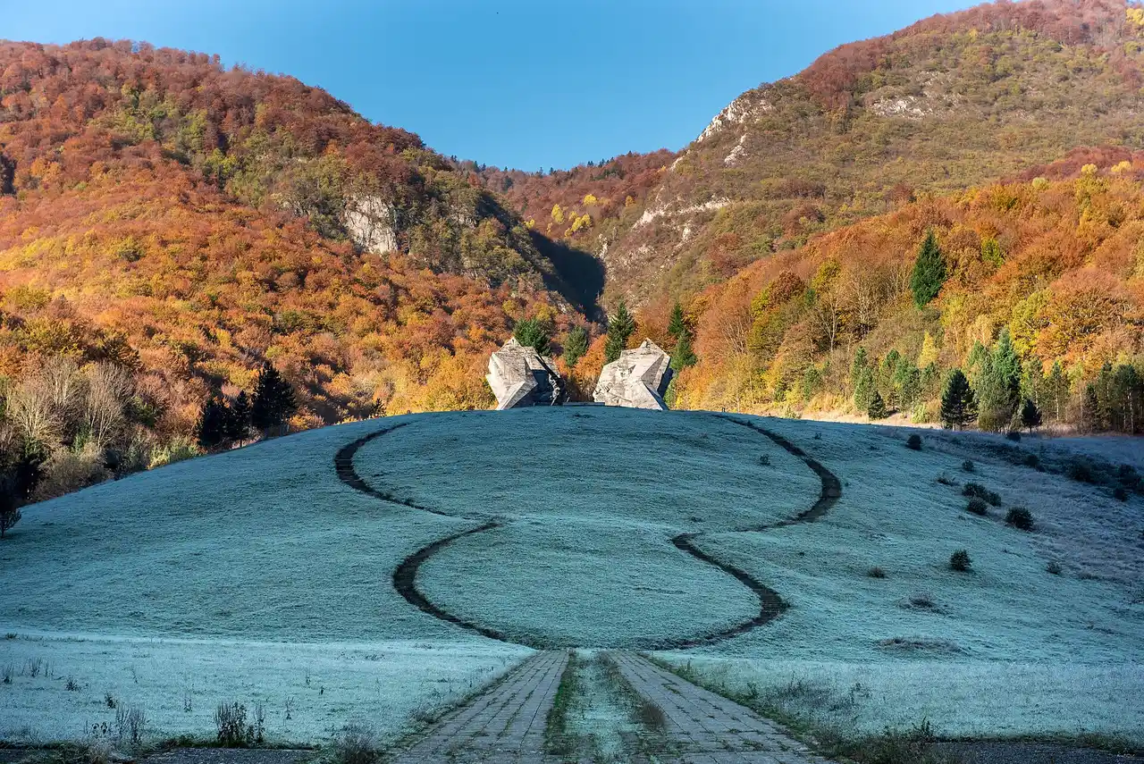 The two great white concrete wings of the Tjentište war memorial standing on a hillside in the Sutjeska valley