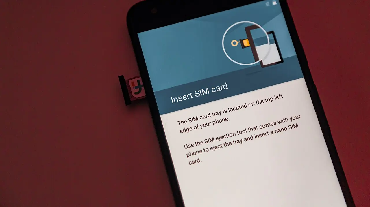 A hand slotting a nano SIM card into the tray of an Android smartphone