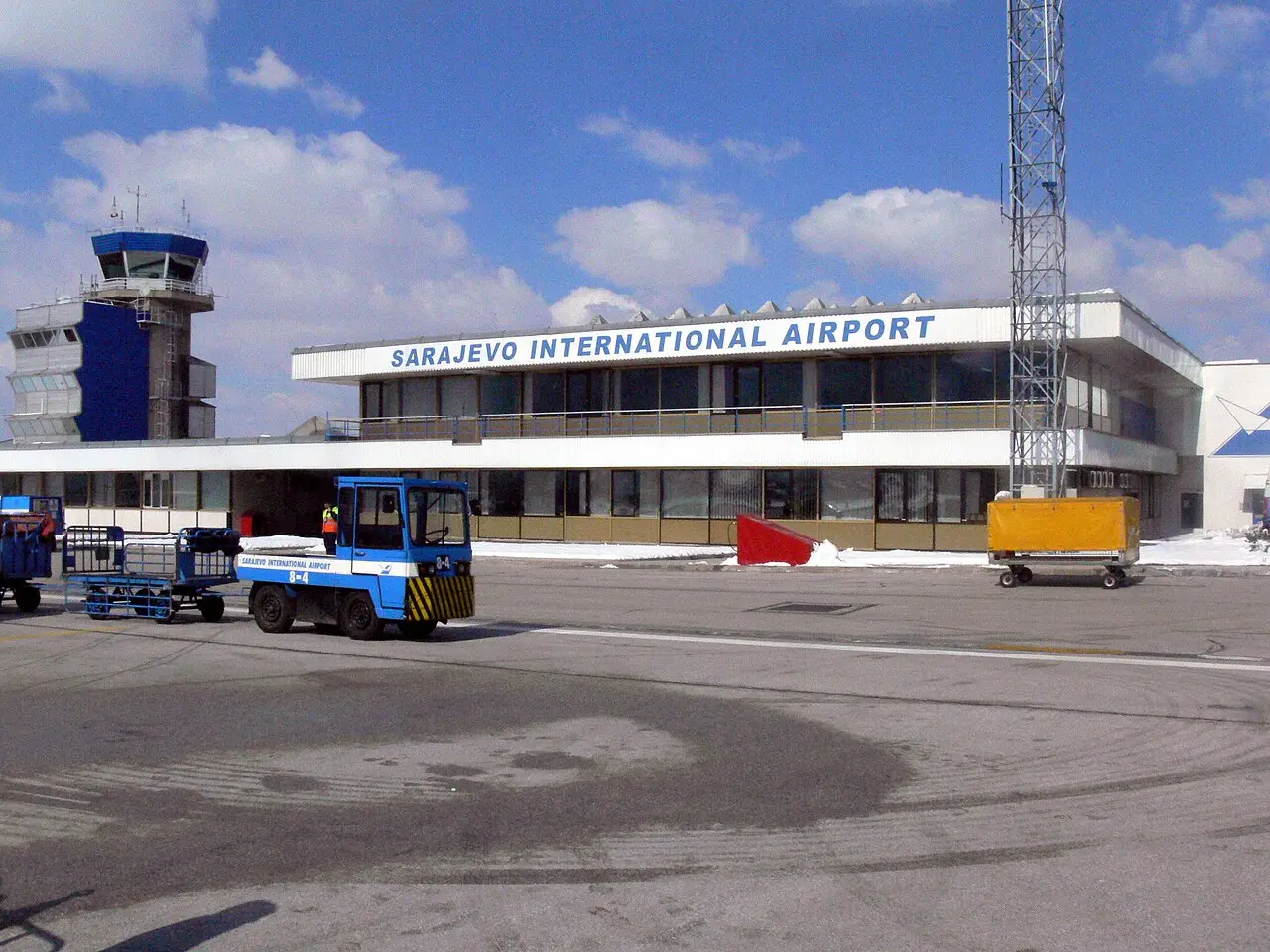 The terminal building of Sarajevo International Airport with the control tower behind it under a clear sky