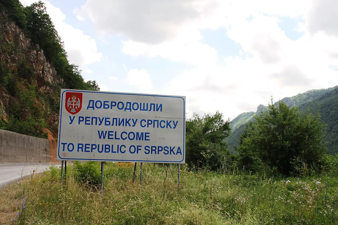 A roadside sign marking the boundary of Republika Srpska on the road out of Sarajevo towards Pale, with hills behind