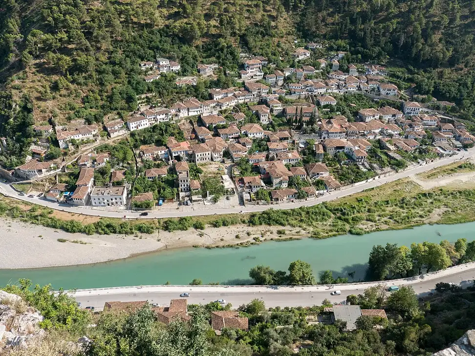 White Ottoman houses stacked up the hillside of Berat under a bright sky