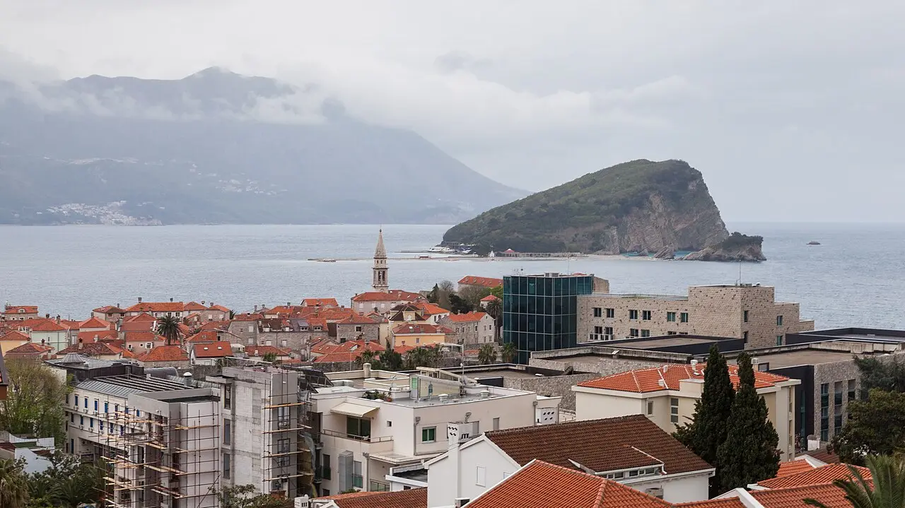 The walled old town of Budva on the Montenegrin coast jutting into a calm Adriatic under low hills