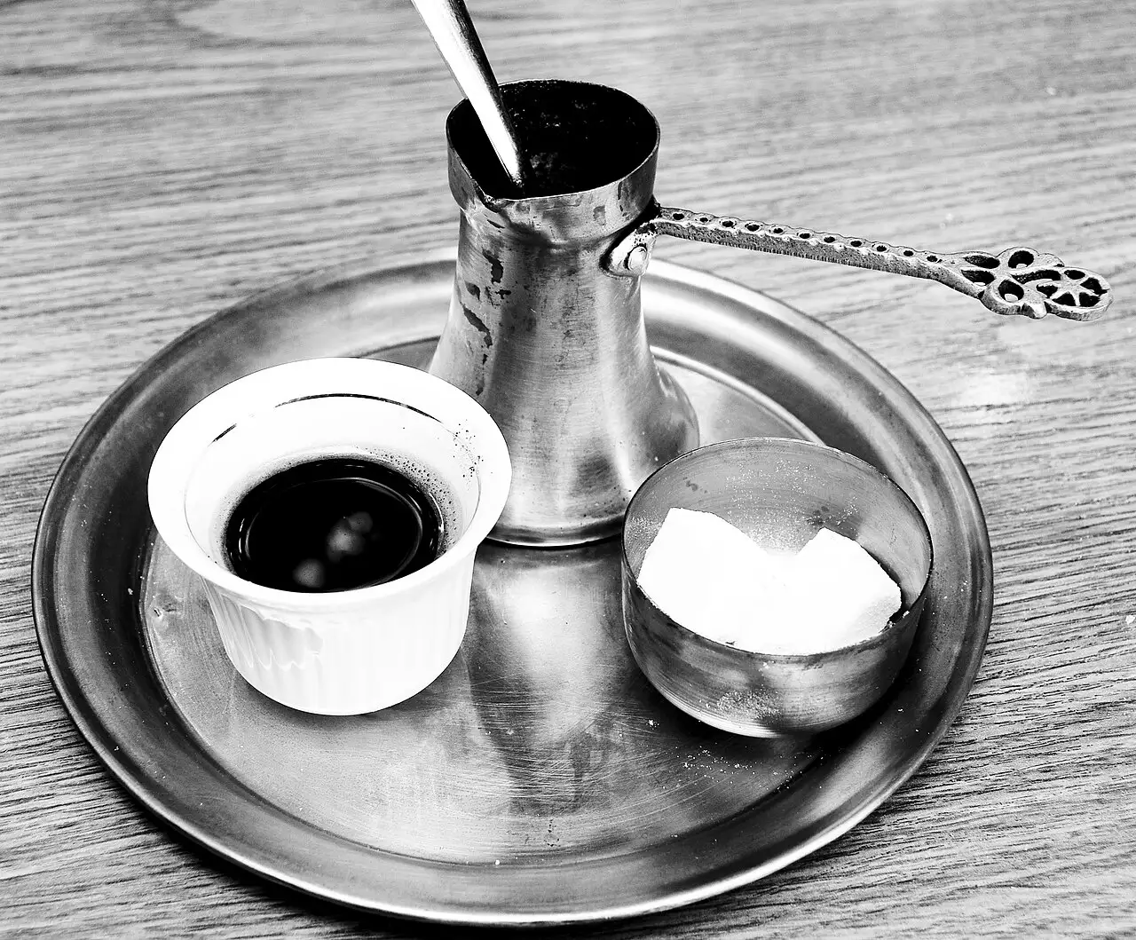 Bosnian coffee served on a metal tray with the copper džezva, a fildžan cup of coffee with a little foam, and a bowl of sugar cubes