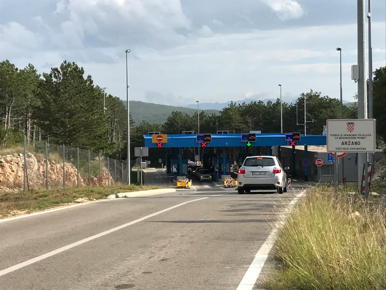 A car waiting at the Aržano border crossing between Croatia and Bosnia and Herzegovina, blue booths and a border sign