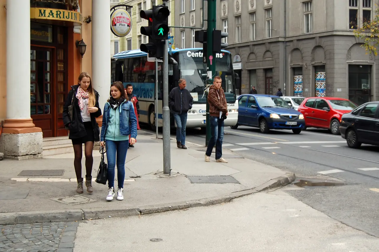 Traffic, a bus and pedestrians at a Marijin Dvor junction in central Sarajevo, trolleybus wires overhead