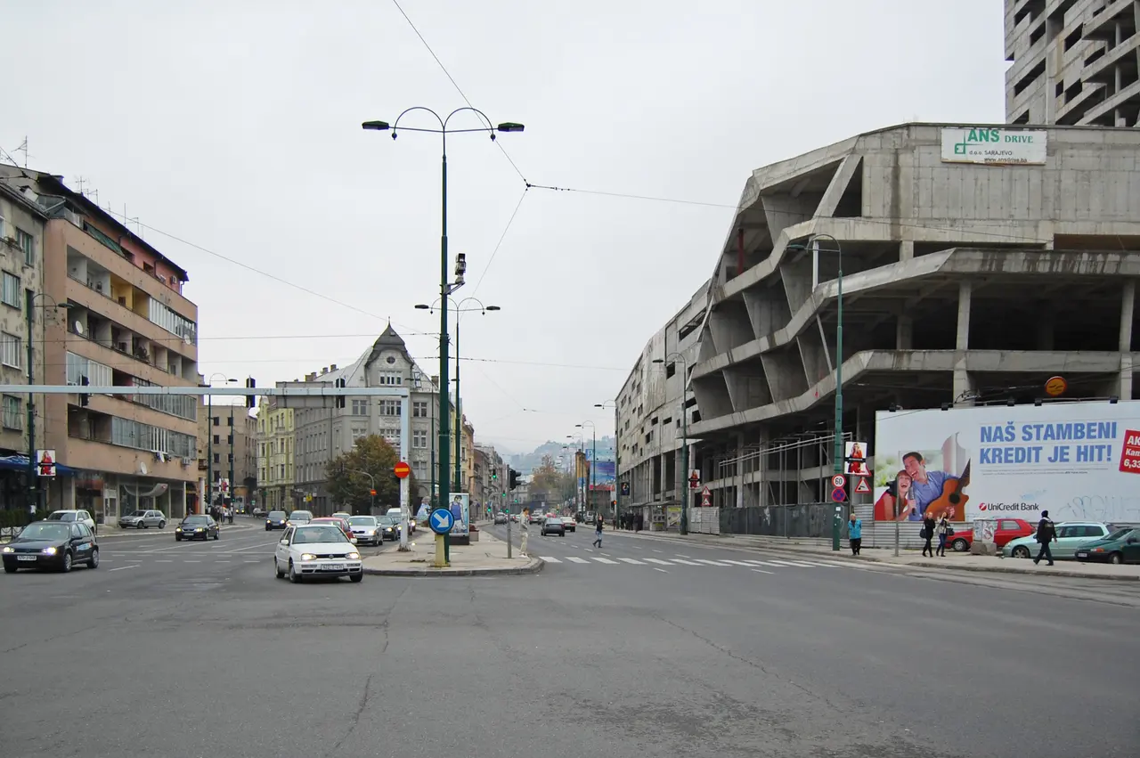 A Sarajevo boulevard with directional signs for Tuzla, Centar and Kovacici-Grbavica, traffic queued at the lights