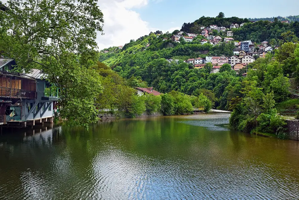 Sarajevo old town reflected in still water, minarets and tiled roofs under the surrounding hills