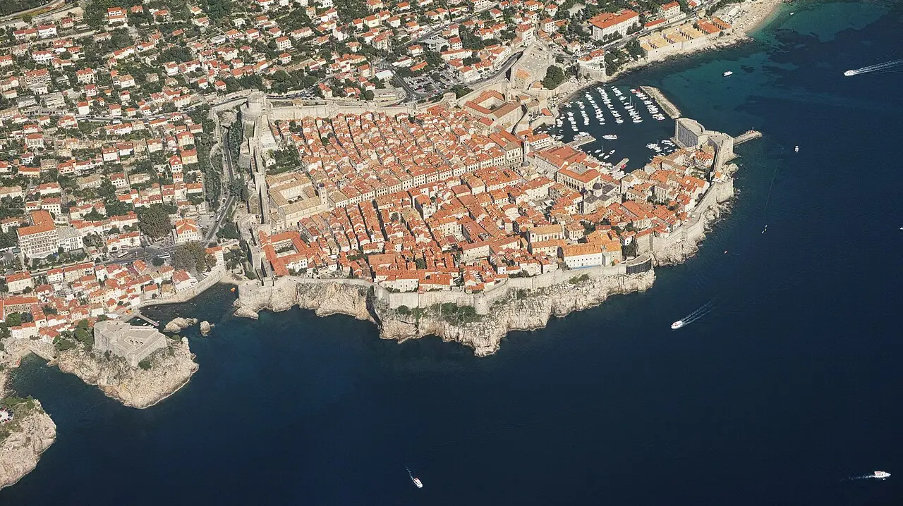 Aerial view of the walled old town of Dubrovnik on its promontory, red roofs ringed by the blue Adriatic