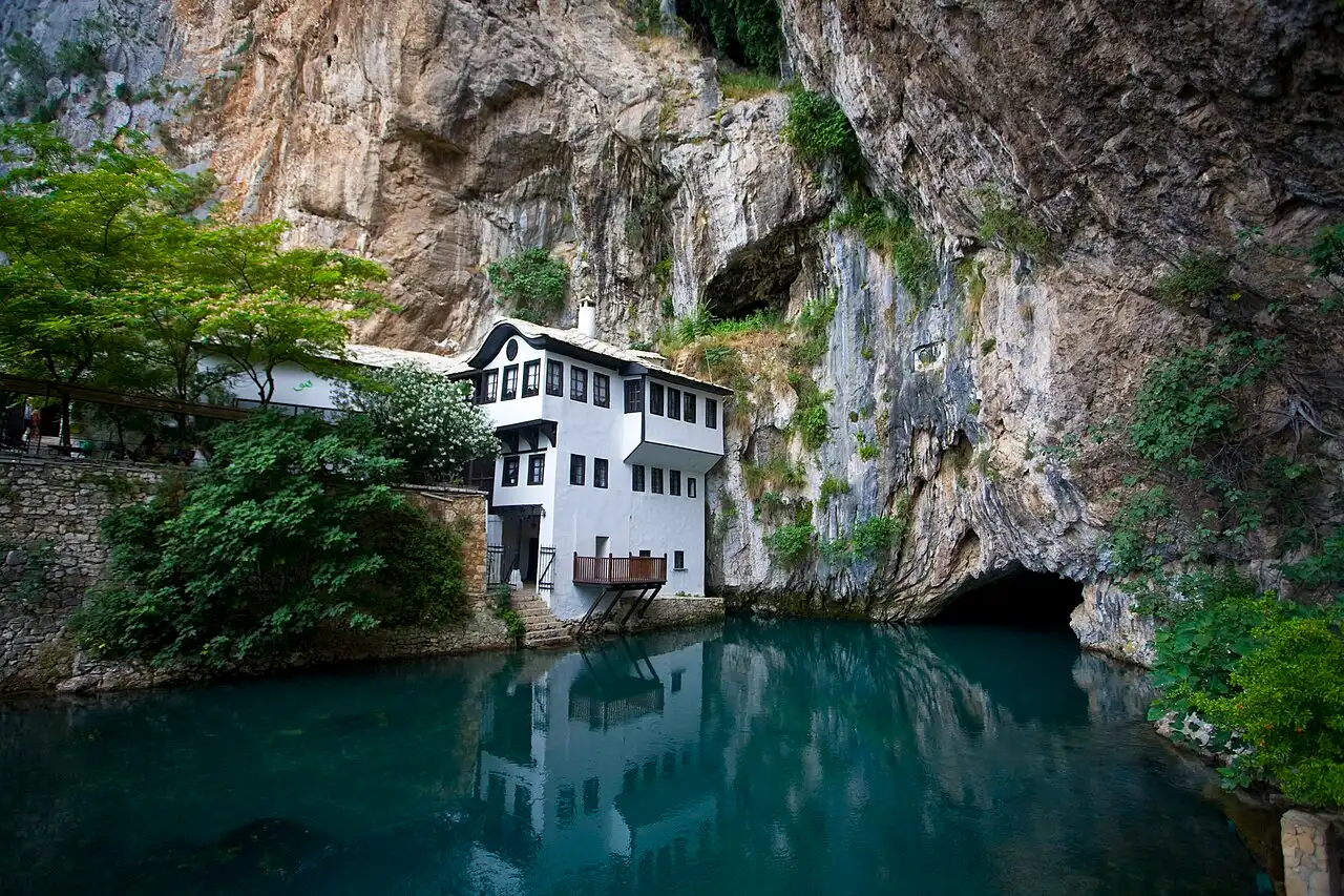 The white Blagaj dervish house built against a limestone cliff beside the clear green Buna spring pool