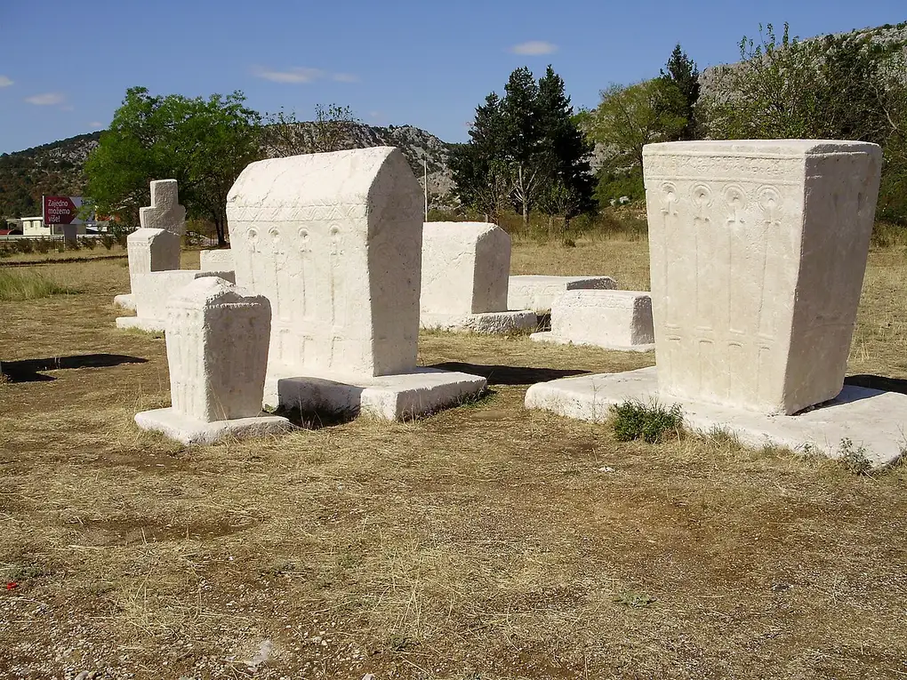 Carved white medieval stecci tombstones standing in the field of the Radimlja necropolis near Stolac