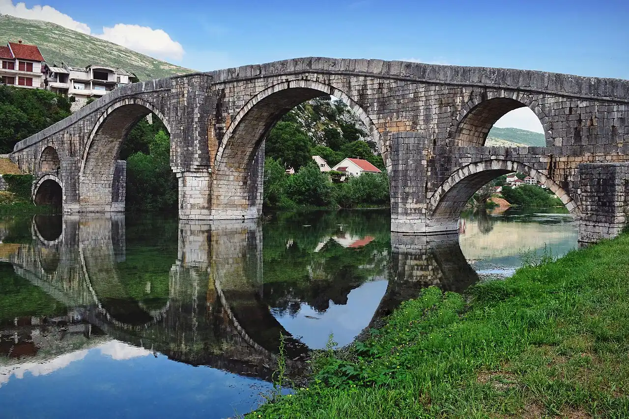 The multi-arched Ottoman Arslanagic stone bridge reflected in the still Trebisnjica river at Trebinje