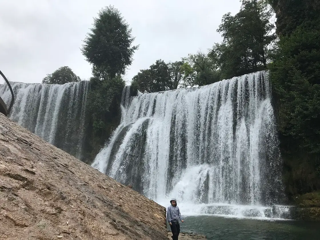 The wide Pliva waterfall dropping over a green tufa barrier in the middle of Jajce town