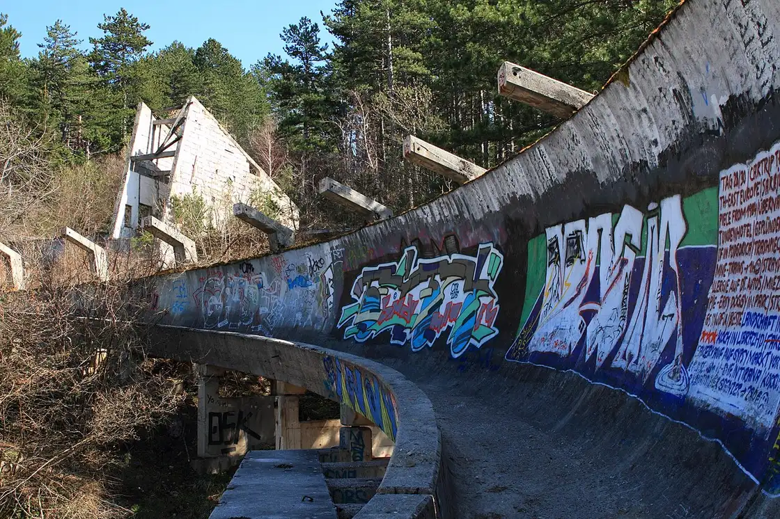 The abandoned 1984 Olympic bobsled track on Mount Trebević, its concrete channel covered in graffiti and running downhill through forest