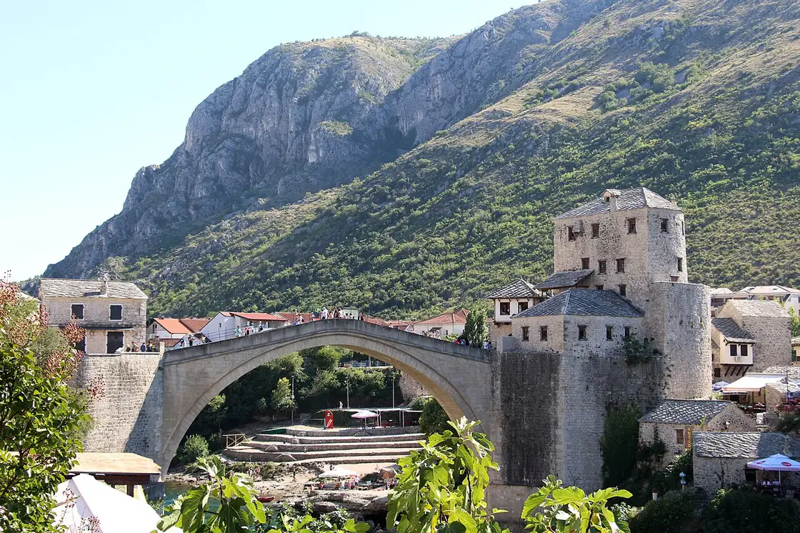 The Old Bridge of Mostar with the bare limestone mountain rising steeply behind it, the reward at the end of the drive