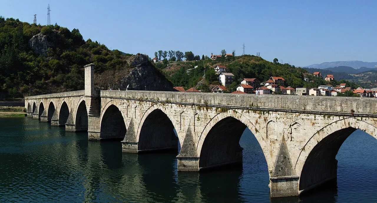 The eleven stone arches of the Mehmed Paša Sokolović bridge stretching across the green Drina at Višegrad