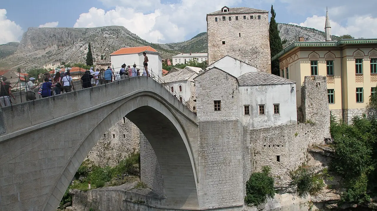 The Old Bridge of Mostar arching over the turquoise Neretva, stone houses and minarets on both banks