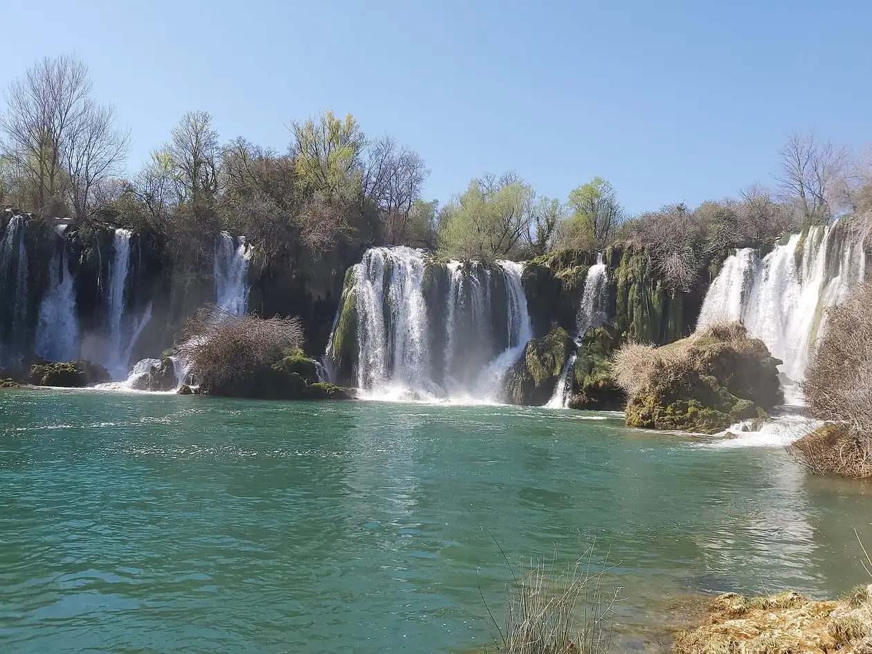 The wide horseshoe of the Kravice waterfalls tumbling into a green pool in Herzegovina