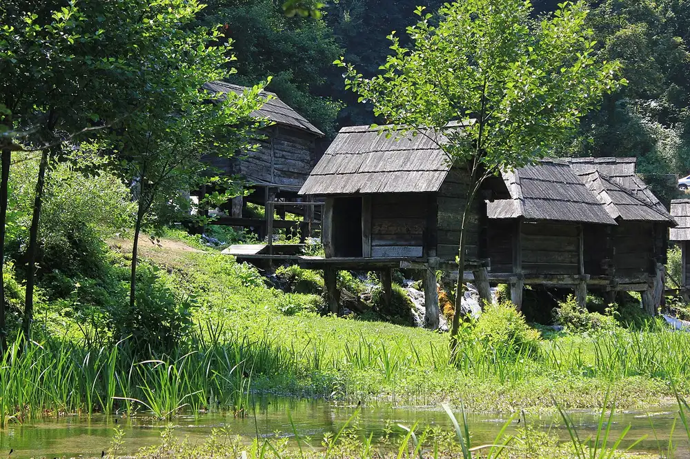 A row of small wooden watermills straddling channels of the Pliva river between the lakes near Jajce