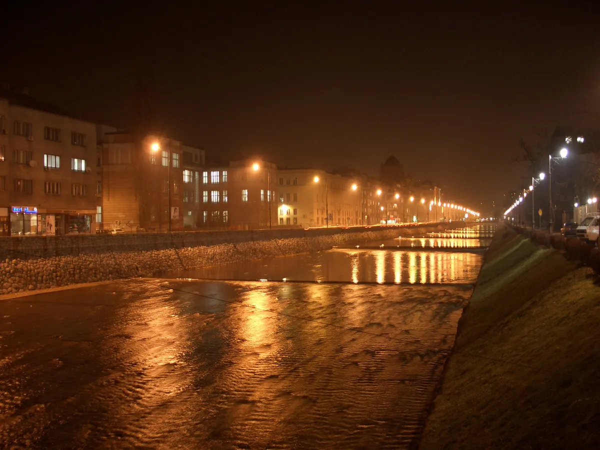 The Miljacka river in central Sarajevo on a misty night, street lamps along both embankments reflected in the water