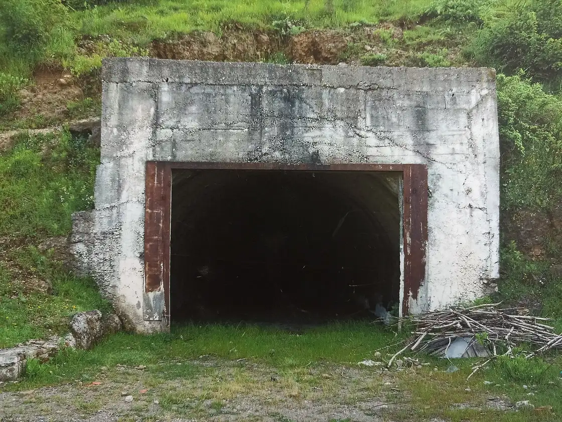 A plain reinforced concrete entrance set into a green hillside, the disguised way in to Tito's ARK D-0 bunker near Konjic