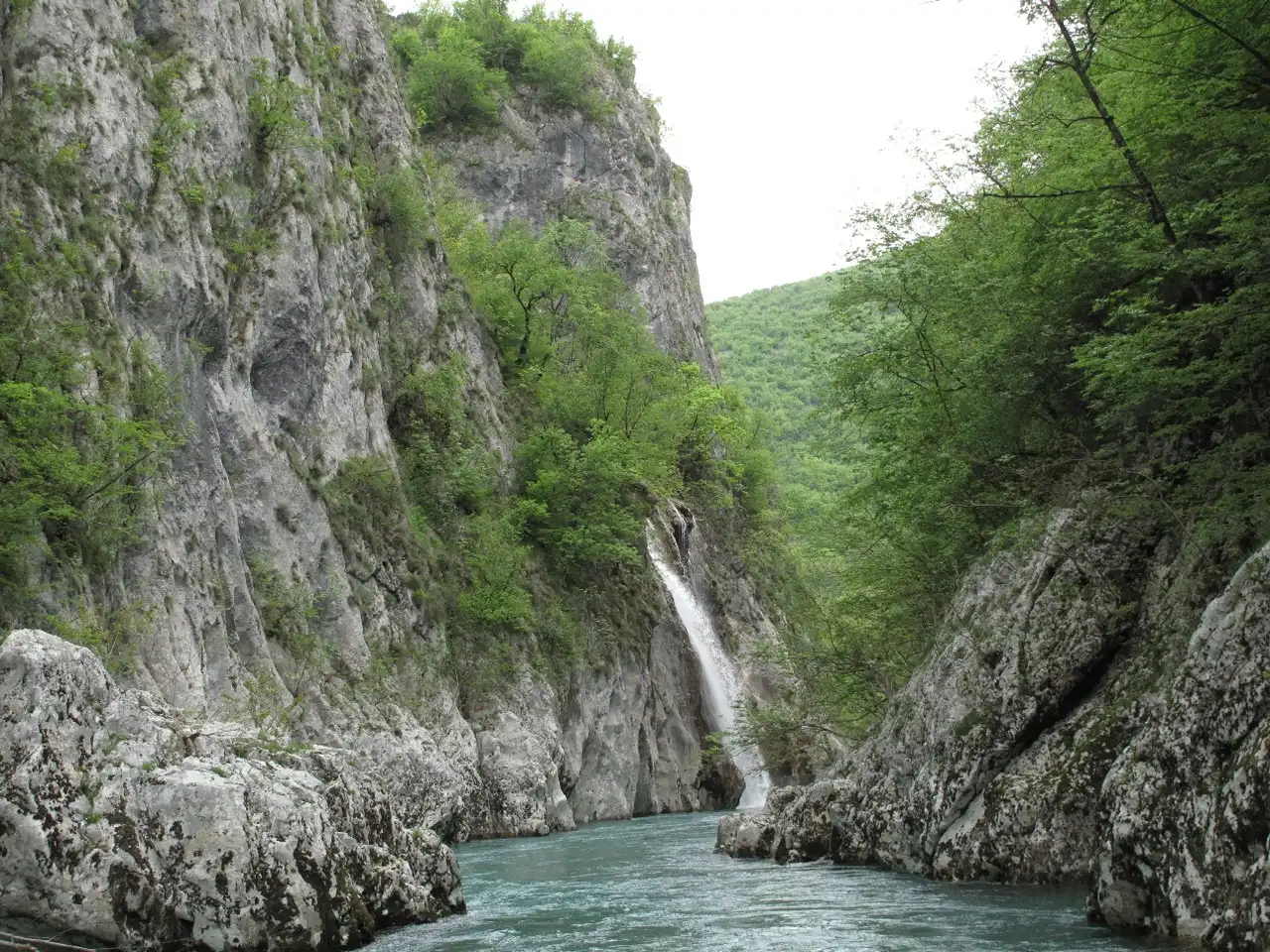 The Neretva running turquoise between tall grey limestone cliffs in a narrow canyon near Konjic