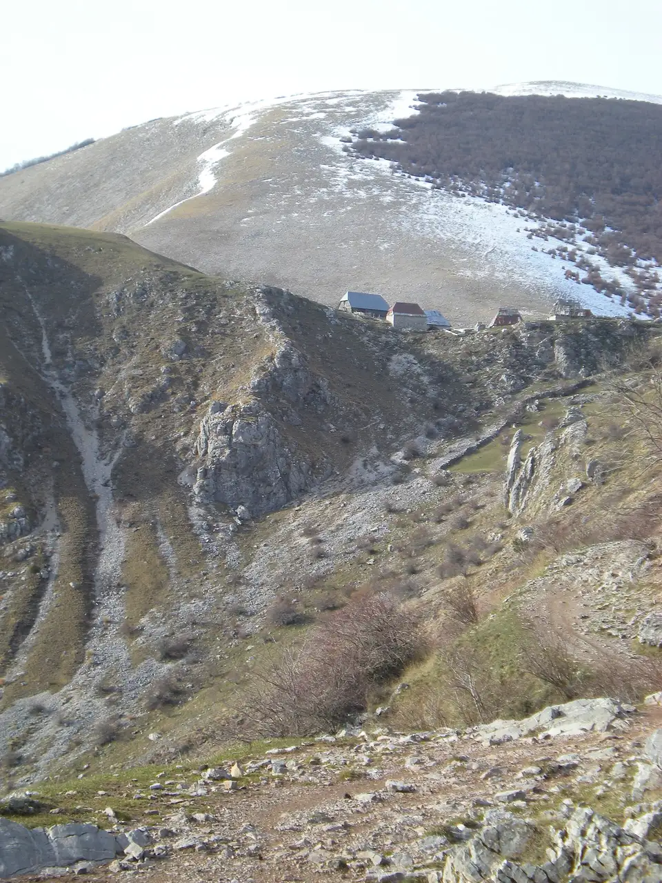 The bare Bjelašnica ridge above the Rakitnica canyon seen from the walking trail, patches of snow on the high slopes and Lukomir in the distance