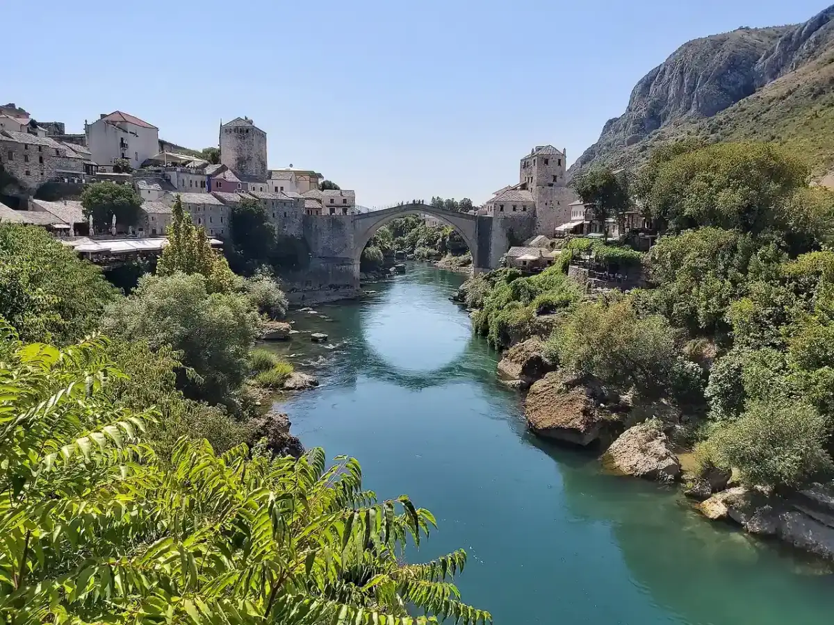 Mostar's Ottoman Old Bridge arching over the turquoise Neretva between stone towers and the old town, the goal of a day trip from Makarska