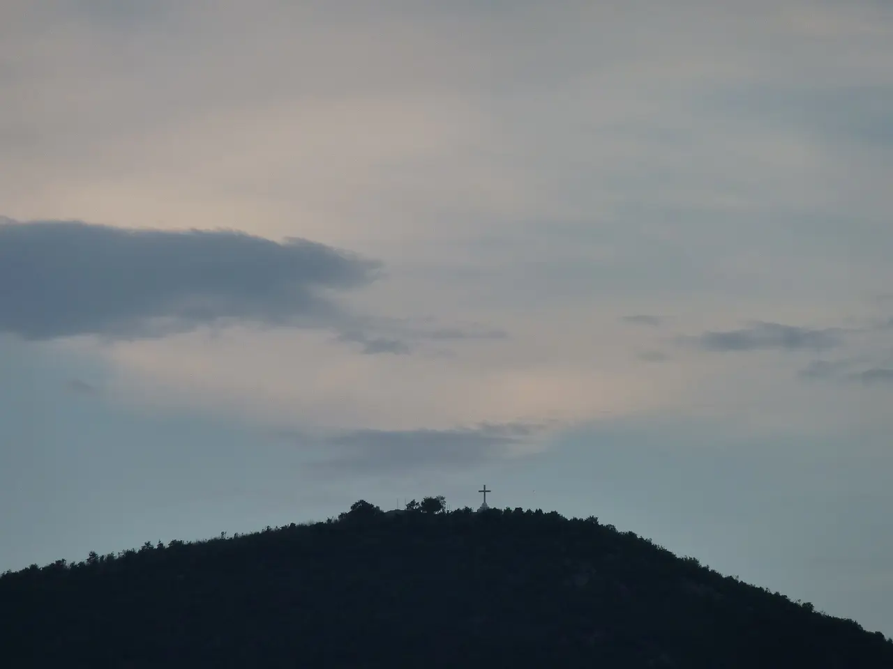 The white concrete cross on the summit of Cross Mountain (Krizevac) in silhouette against a dusk sky