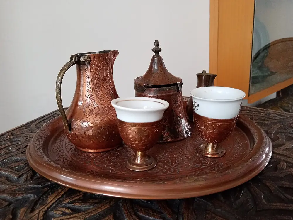 A Bosnian coffee set with a copper džezva, a small cup and a piece of Turkish delight on a tray