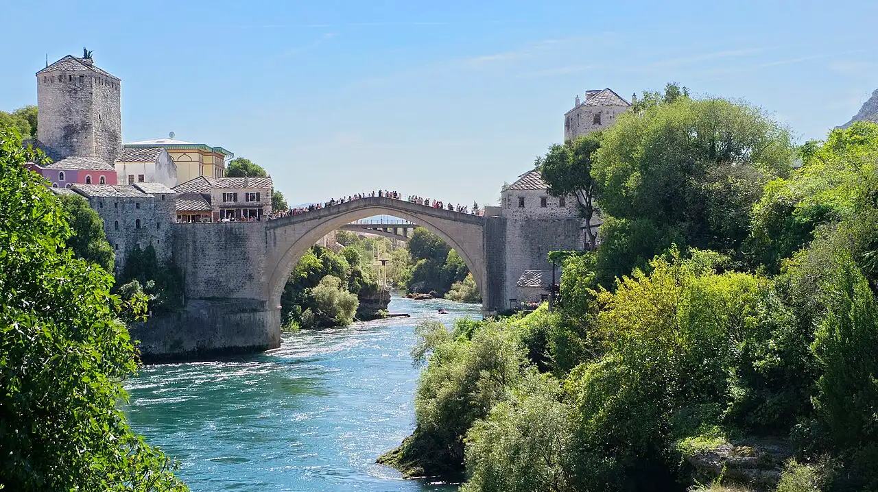Landscape view of Mostar Old Bridge and stone houses above the Neretva under a clear sky