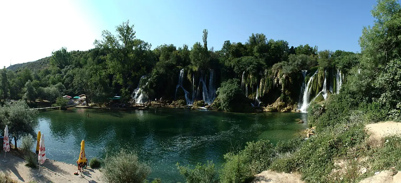 Wide curtain of the Kravice waterfalls tumbling into a green pool