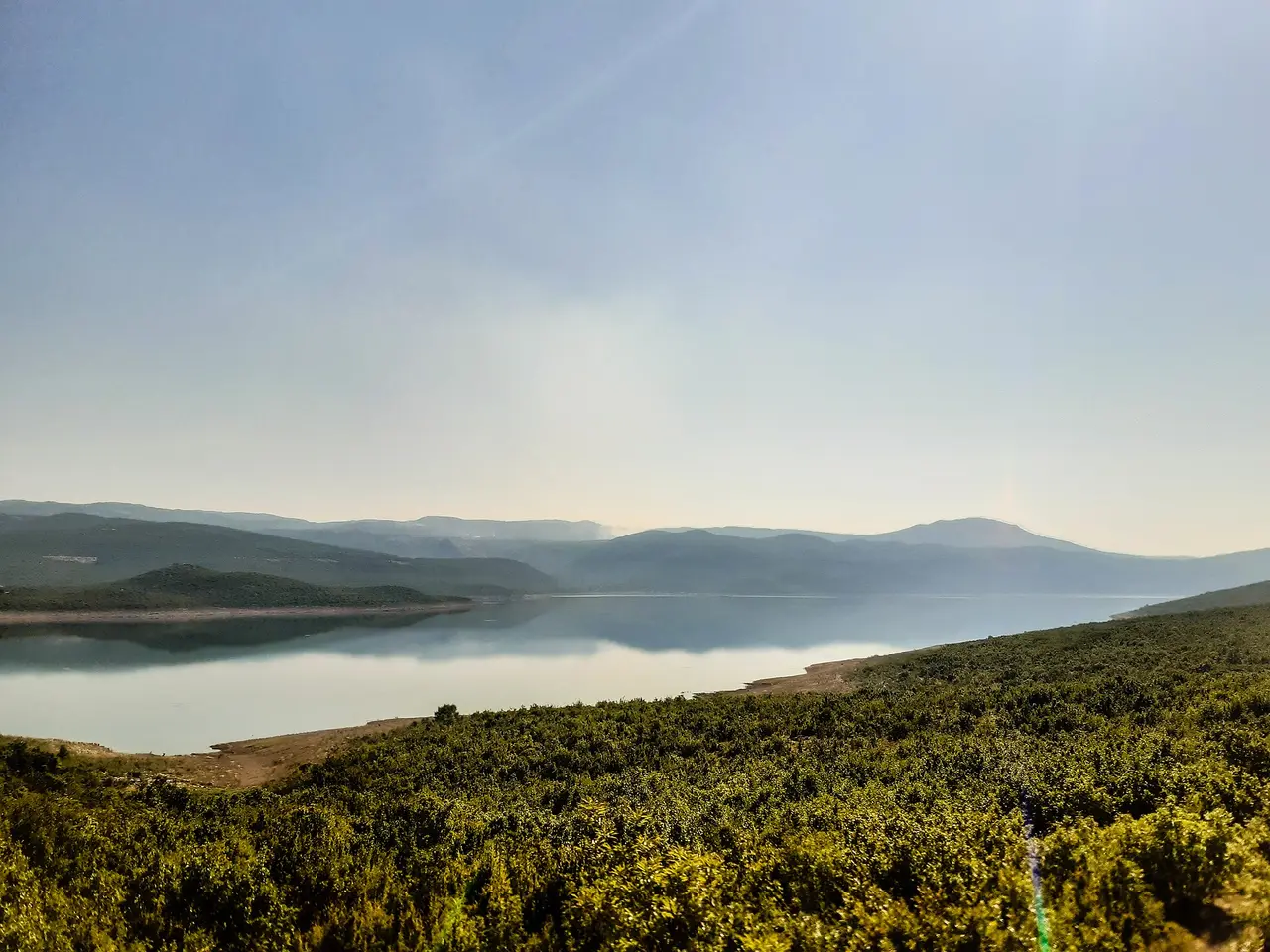 The calm blue water of Lake Bileca (Bilecko jezero) among low green hills in eastern Herzegovina, on the route from Mostar to the coast