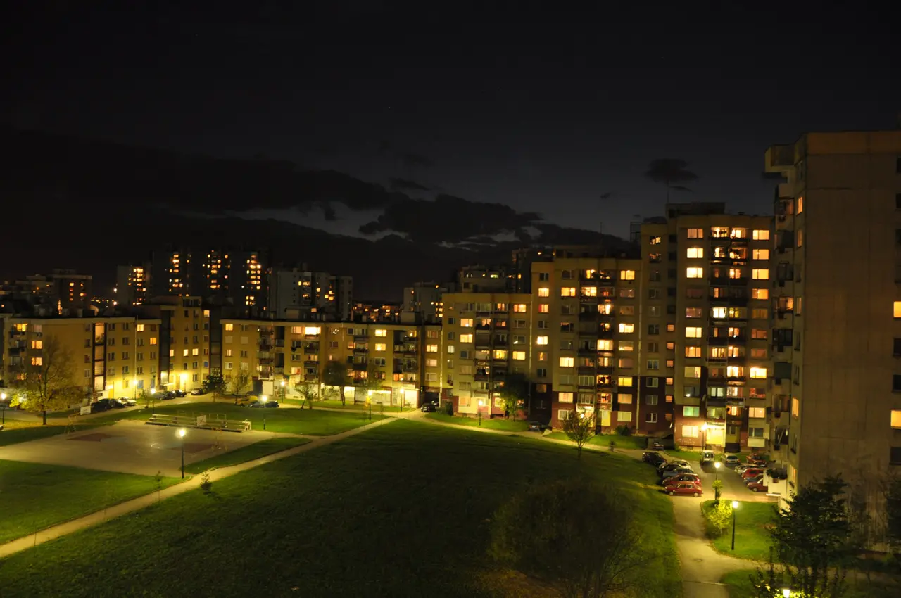 Lit windows of the Alipašino Polje housing estate in Sarajevo at night above a dark green park